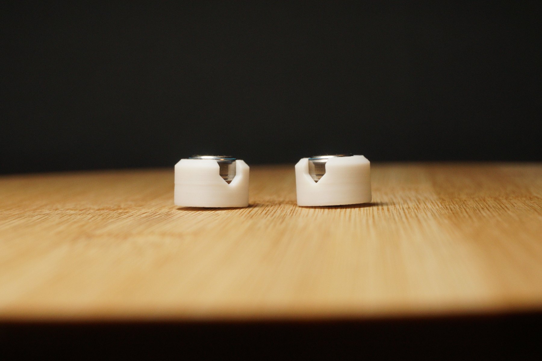 Zwei weiße PX640-Adapter nebeneinander auf einem Holztisch.